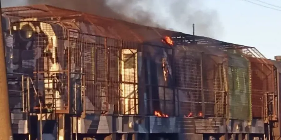 Палаючий вагон приміського поїзда з металевими ґратами та полум’ям