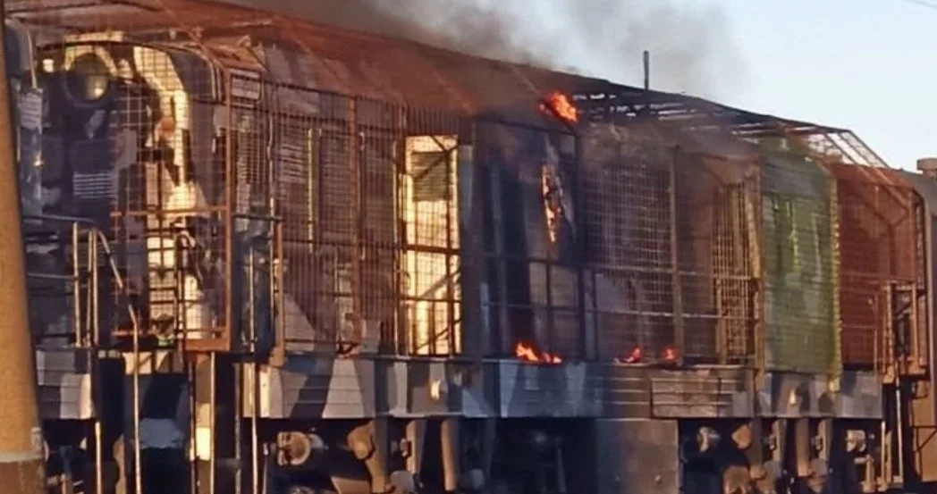 Палаючий локомотив із металевими ґратами, полум’ям і димом після удару